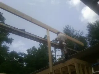 Carpenter setting a ridge beam over a new addition frame — Ice Dam Removal by Roofing Brothers in Scottville