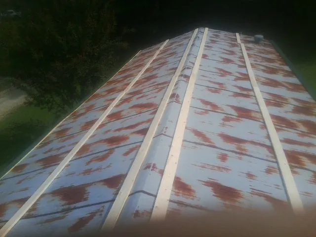 Rusted metal roof panels with new wood purlins before replacement — Storm Damage Roof Repair in Scottville by Roofing Brothers