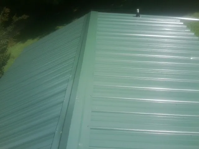 New green metal panels meeting at the ridge of a roof — Flat Roof Repair work by our crew in Scottville