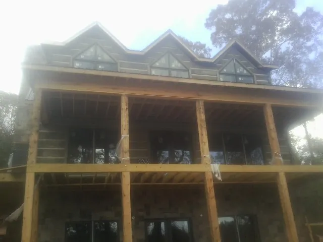 Dormers and porch framing on a large log home under construction — Roof Coating work by our crew in Scottville