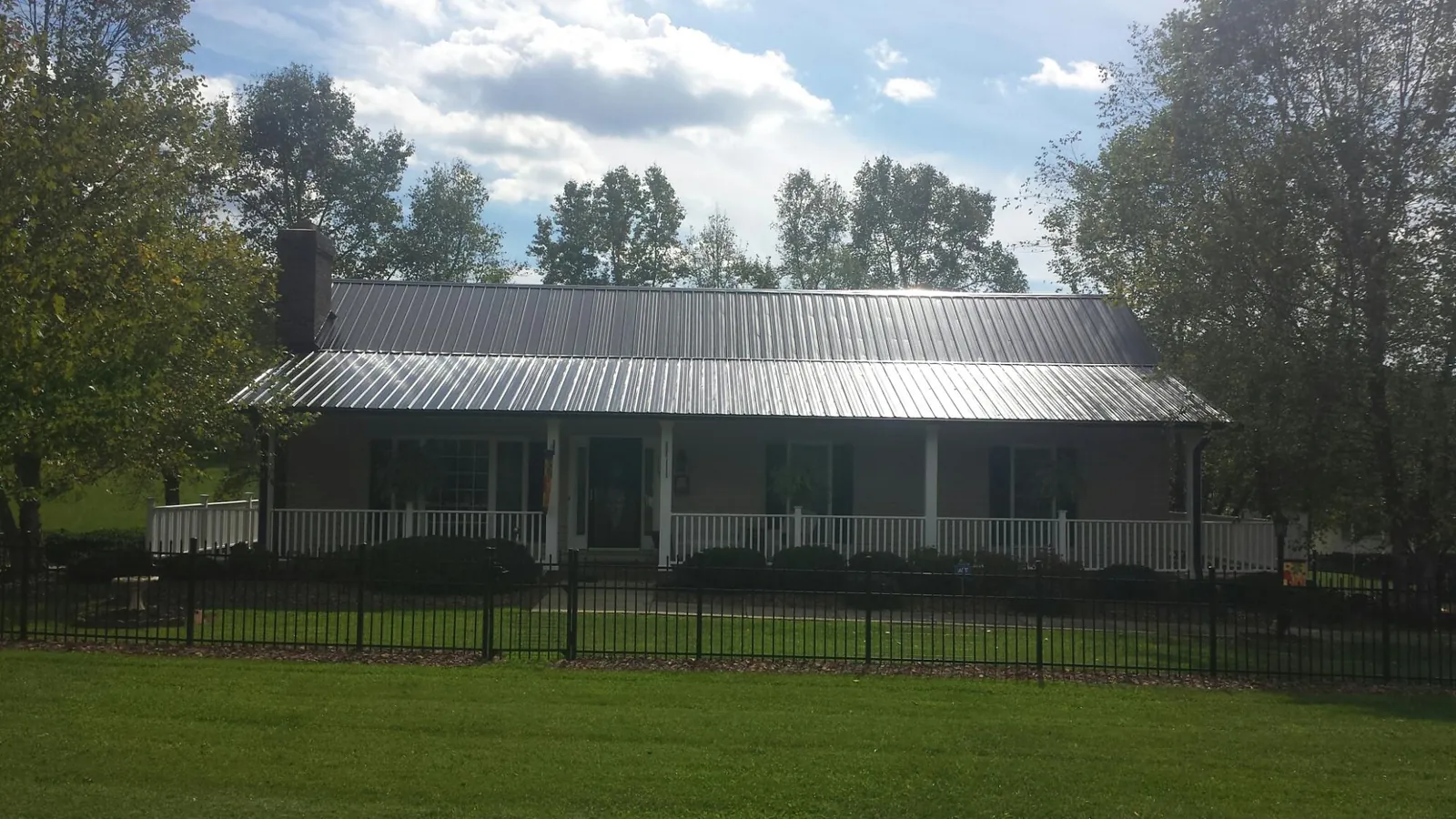 Gray metal roof on a brick ranch with a full width front porch — Gutter Guard Installation work by our crew in Scottville