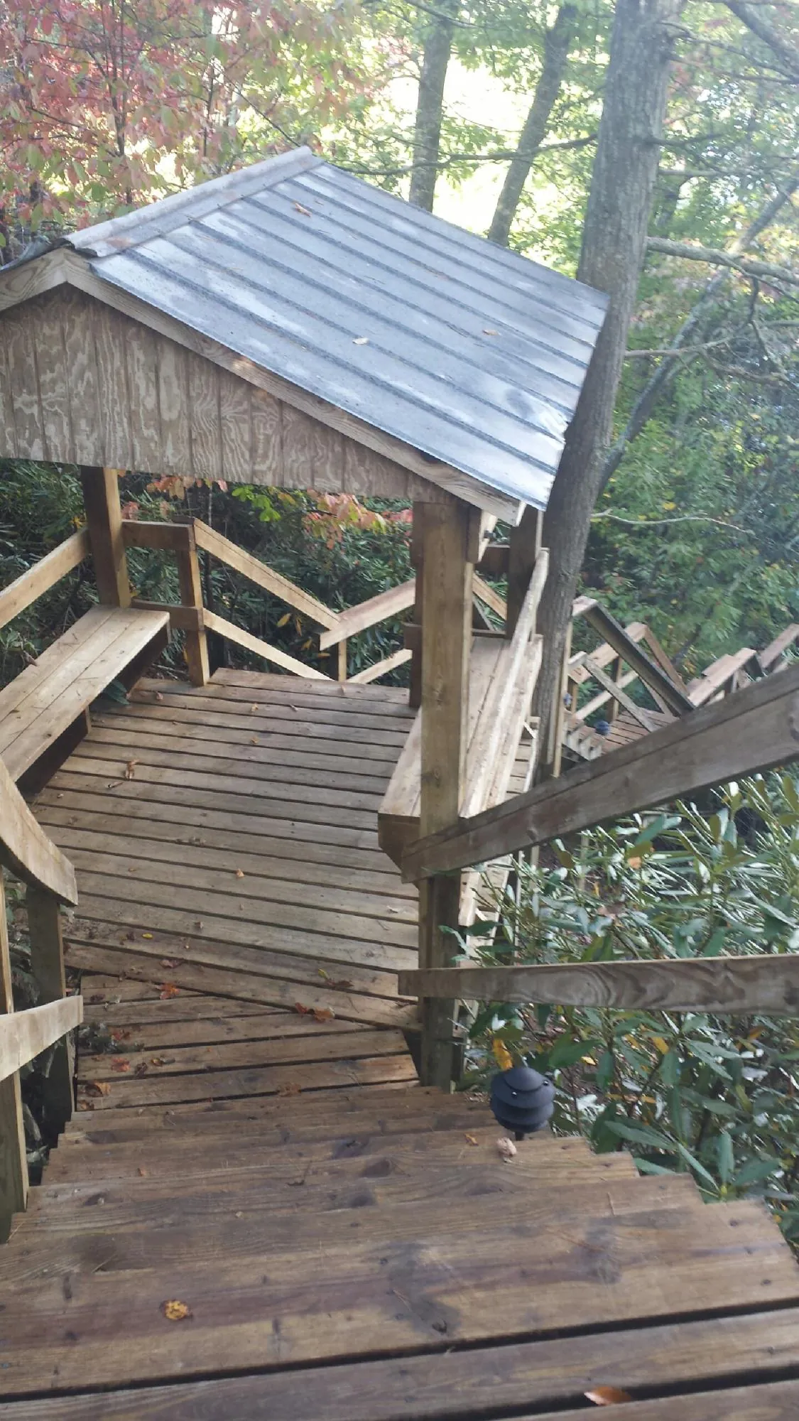 Metal roofed shelter over wooden steps on a wooded walkway — Skylight Repair & Installation work by our crew in Scottville