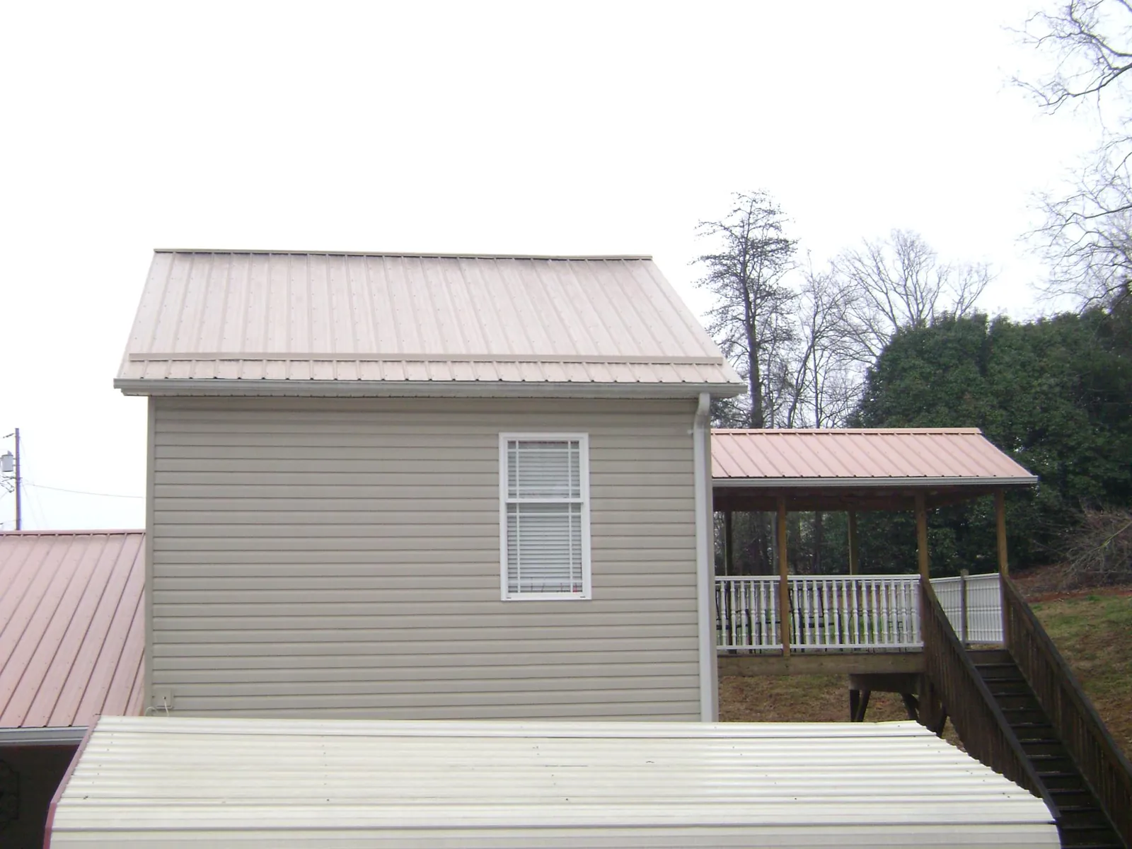 Tan metal roofs on a two story addition and attached porch, from a Roof Replacement job in Scottville