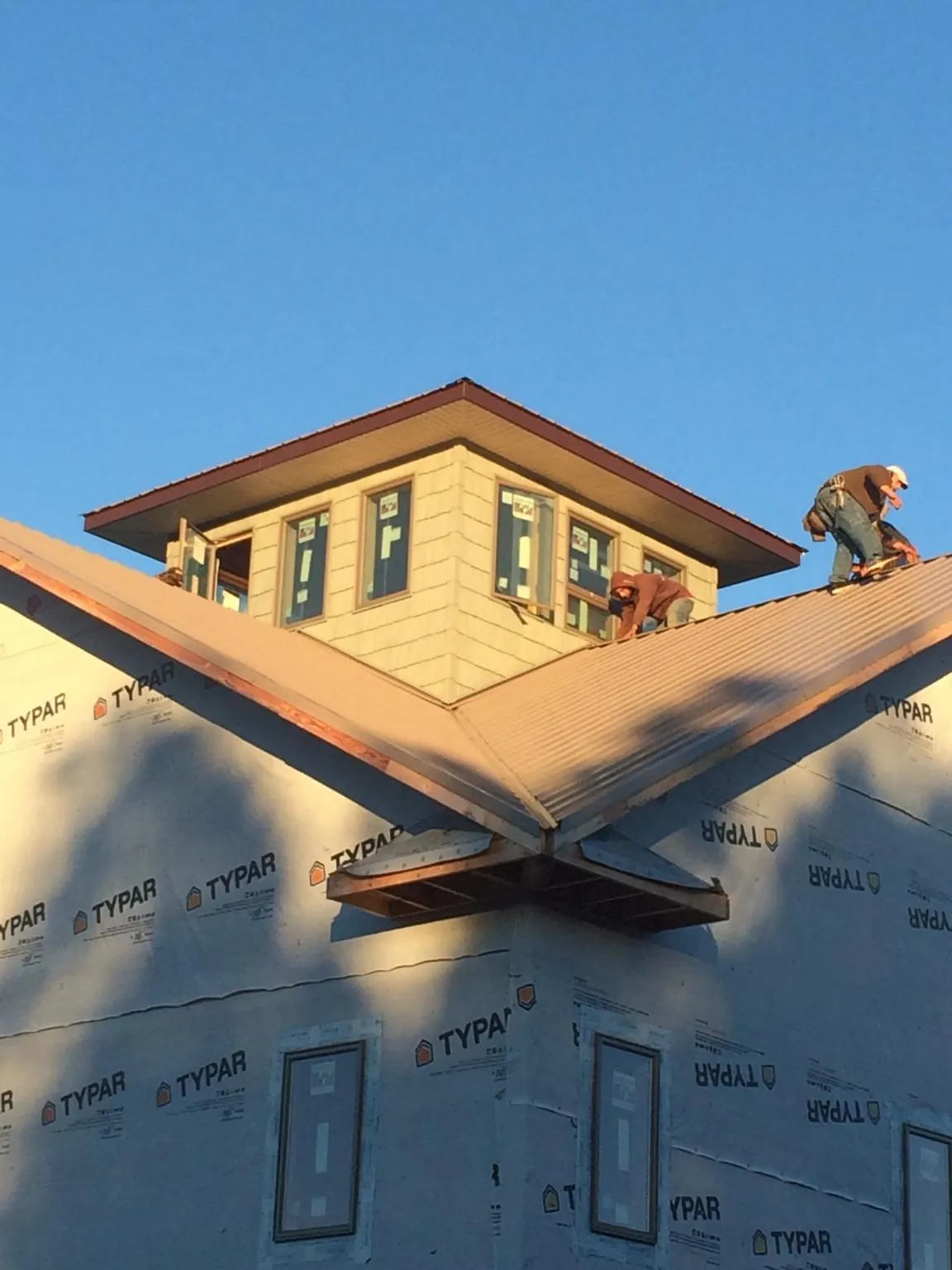 Roofers working around a rooftop cupola on a new metal roof at sunset — Roof Waterproofing in Scottville by Roofing Brothers